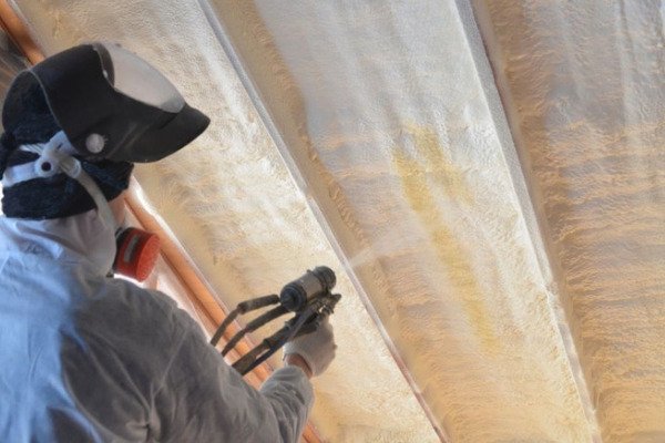 A worker spraying foam insulation in a residential attic.