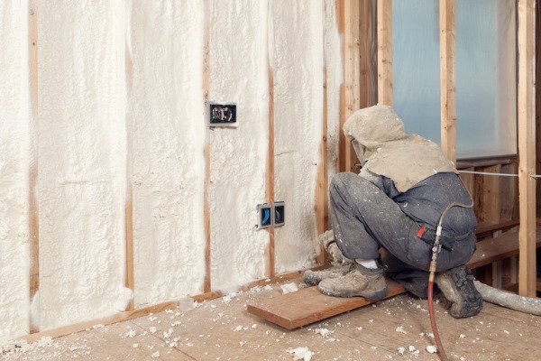Worker insulating a residential home using spray foam insulation.